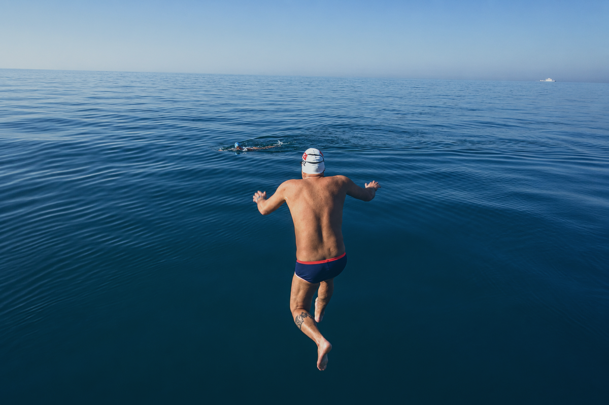 A swimmer entering calm blue open water