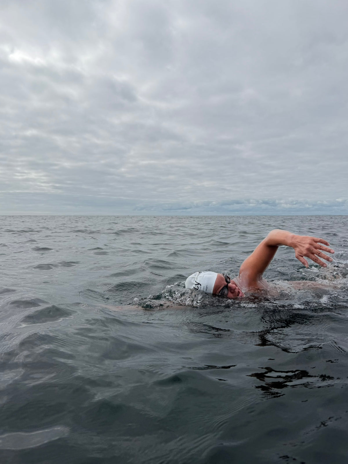 An open-water swimmer beneath a cloudy sky